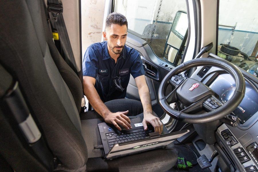 Richard running OEM diagnostic laptop inside truck cab at NH Repairs