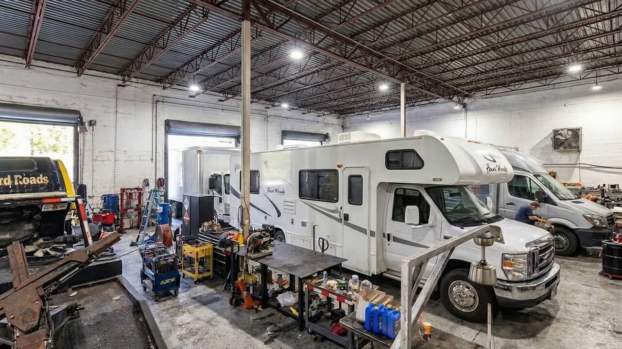 Three commercial box trucks parked outdoors at a repair facility, including a Nationwide Haul service truck with branding for sales, service, and leasing